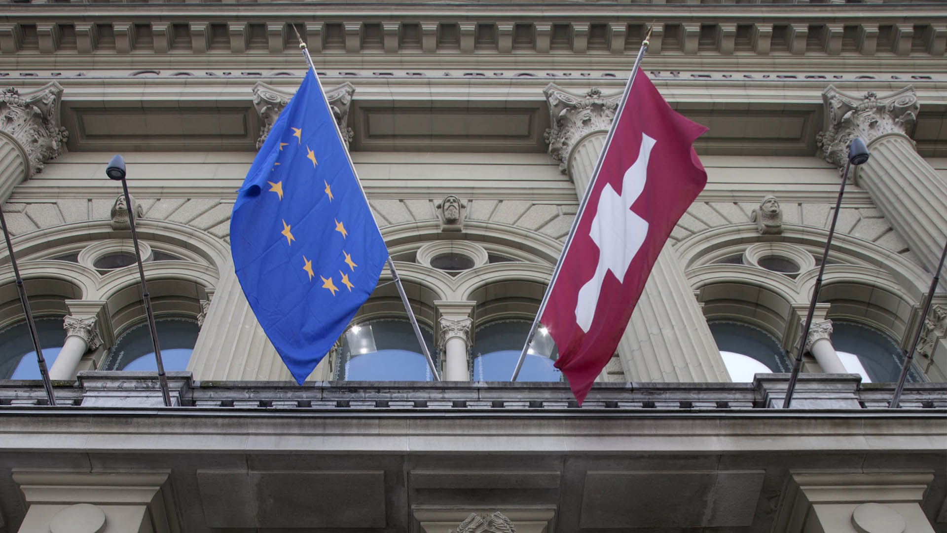 Fassade des Bundeshauses mit Flaggen der Schweiz und der EU.