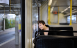 Eine Person sitzt allein in einem regional verkehrenden Zug.