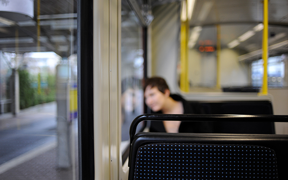 Eine Person sitzt allein in einem regional verkehrenden Zug.