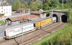 Ein Zug mit Sattelaufliegern fährt in einen Tunnel ein.