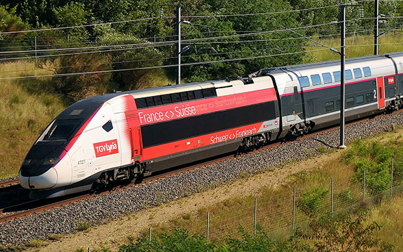 Ein TGV Lyria Zug fährt durch die Landschaft zwischen der Schweiz und Frankreich.