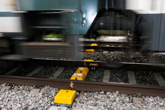 Ein Zug fährt über gelbe Kästchen, die zwischen den Gleisen montiert sind.