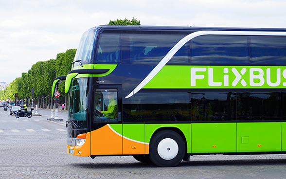 Ein hellgrün-oranger Flixbus unterwegs im Strassenverkehr.