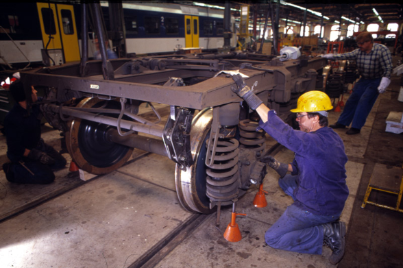 A railway employee checks the braking system on the wheel of a railway wagon.