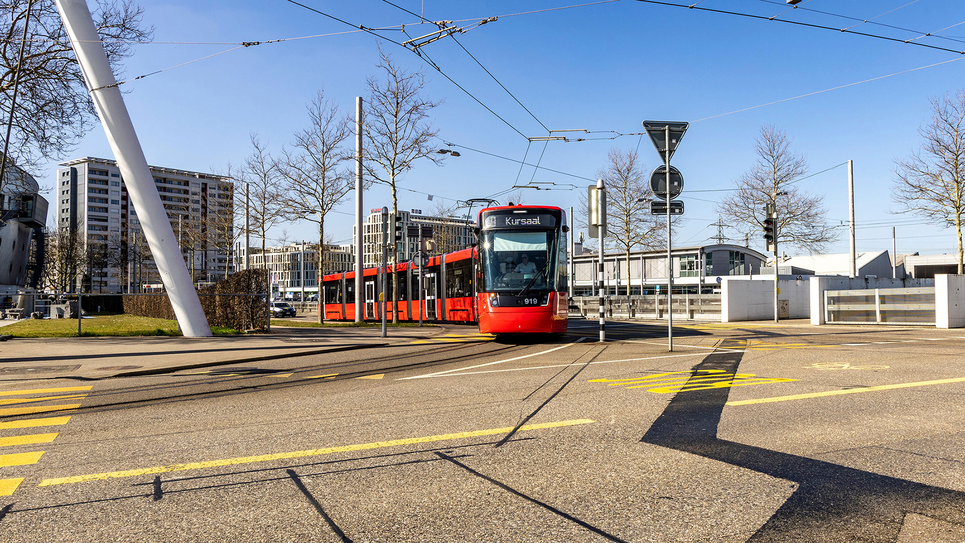 Un tramway jaune devant la façade rouge de la mairie de Bâle. (OFT)