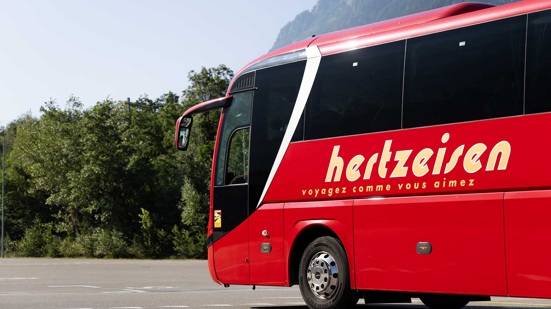 Un autocar rouge de Hertzeisen en route.