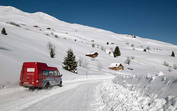 Un minibus descend vers la vallée sur une route enneigée 