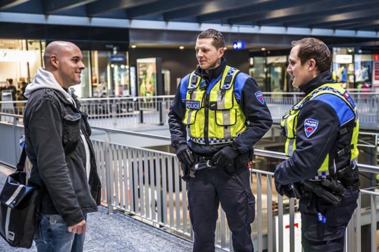 Un usager en discussion avec deux collaborateurs en uniforme de la police des transports.